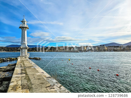 White lighthouse by lake promenade with city skyline and mountains in background. High quality photo White lighthouse by lake promenade with city skyline and mountains in background. High quality photo 128739686