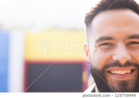Young man smiling broadly in front of colorful painted mural outdoors, enjoying sunny mood Young man smiling broadly in front of colorful painted mural outdoors, enjoying sunny mood 128739949