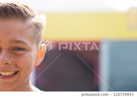 Child girl smiling outdoors in front of building facade with yellow band, showing joy, copy space 128739955