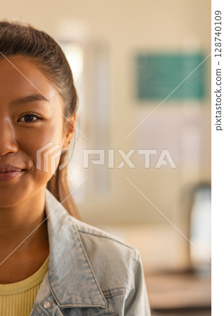 Asian woman studying in classroom at desk, wearing denim jacket and yellow top, copy space Asian woman studying in classroom at desk, wearing denim jacket and yellow top, copy space 128740109