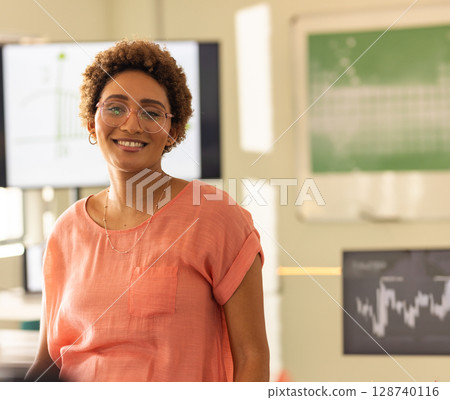 Woman standing in laboratory setting, with histogram and line graph monitors and green chart board Woman standing in laboratory setting, with histogram and line graph monitors and green chart board 128740116