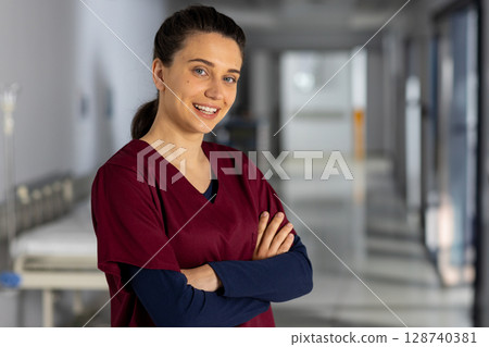 African American nurse smiling with arms crossed in hospital corridor, gurney visible, copy space 128740381