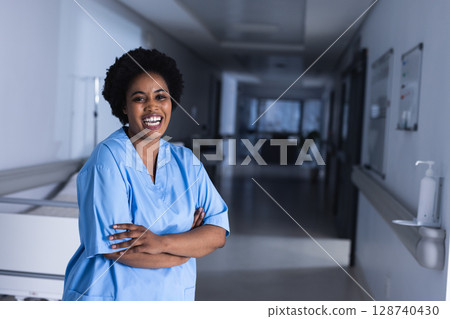 African American nurse standing in hospital corridor, with medical cart, hand sanitizer, whiteboard 128740430