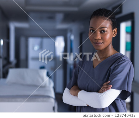 Young African American nurse standing in hospital corridor amid patient bed, medical equipment 128740432