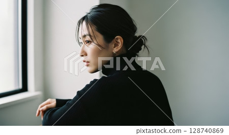窗邊一位穿著黑色高領毛衣的女子的肖像照片 128740869