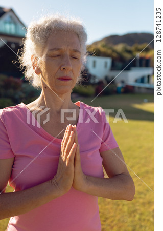 Senior woman practicing meditation in backyard garden, enjoying peaceful moment of mindfulness Senior woman practicing meditation in backyard garden, enjoying peaceful moment of mindfulness 128741235