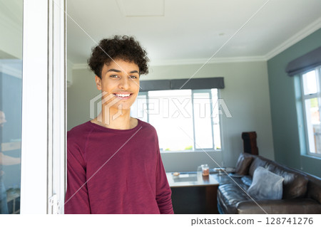 Man standing partially in sliding glass door frame in living room with large window, copy space 128741276