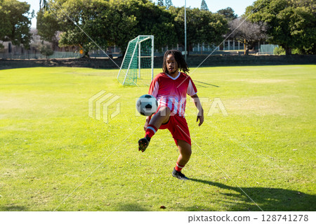 male soccer player juggling black-and-white ball on soccer field at green goal net, showing skill 128741278