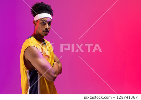 Man standing arms crossed in studio with yellow jersey and white headband, copy space Man standing arms crossed in studio with yellow jersey and white headband, copy space 128741367