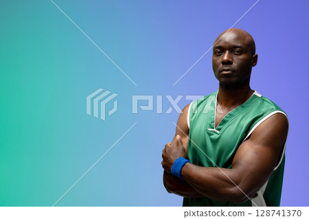 African American man standing arms crossed in studio with basketball jersey, wristband, copy space 128741370