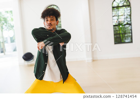 Man dancing in modern dance studio with glass doors, arched window and black seat Man dancing in modern dance studio with glass doors, arched window and black seat 128741454