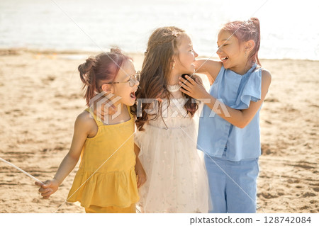 Three funny laughing girls on the beach having fun together 128742084
