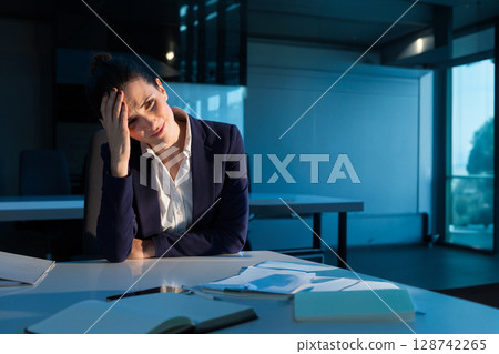 Young businesswoman sitting at conference table in office boardroom, working with notebooks and pen 128742265