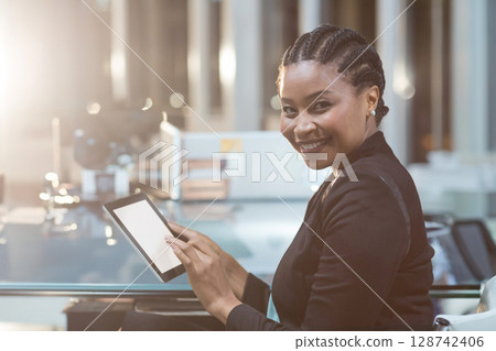 African American woman holding tablet with blank screen at desk in open-plan office, copy space 128742406