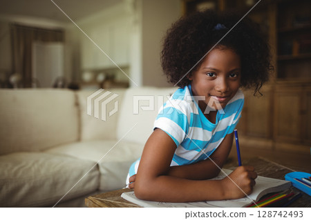 African American woman drawing with pencil in notebook on wooden table in living room, copy space African American woman drawing with pencil in notebook on wooden table in living room, copy space 128742493