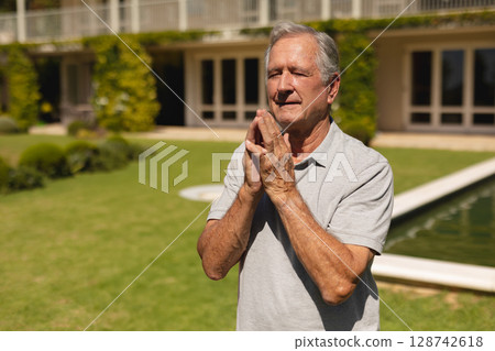 Senior man standing on lawn in front of house with reflecting pool, climbing ivy, copy space Senior man standing on lawn in front of house with reflecting pool, climbing ivy, copy space 128742618