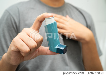 Asthma and chronic obstructive pulmonary disease COPD, Asian young man using metered dose inhaler MDI. 128742830