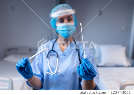 Female healthcare worker holding sterile swab, sample tube in hospital lab with stethoscope 128743001
