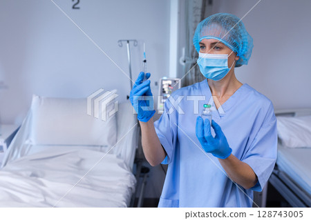 Female nurse preparing injection with syringe and vial in hospital room, copy space 128743005