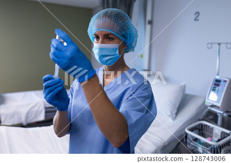 Mid-adult female nurse drawing medication vial into syringe in hospital room, with infusion pump 128743006