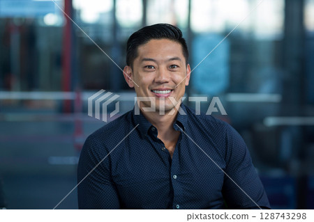 Asian man sitting in office lounge, smiling warmly at camera and projecting professional warmth Asian man sitting in office lounge, smiling warmly at camera and projecting professional warmth 128743298