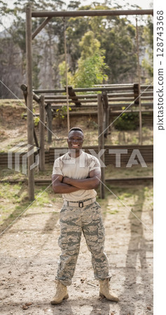 African American young man standing at wooden obstacle course outdoors, crossing arms and smiling African American young man standing at wooden obstacle course outdoors, crossing arms and smiling 128743368