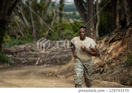 African American man running on dirt trail in forest, dodging exposed roots and rocks, copy space African American man running on dirt trail in forest, dodging exposed roots and rocks, copy space 128743370
