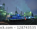 A diesel locomotive weaving through the illuminated factory 128743535