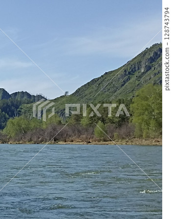 Picturesque mountain river landscape with lush vegetation and clear blue sky above scenery Picturesque mountain river landscape with lush vegetation and clear blue sky above scenery 128743794