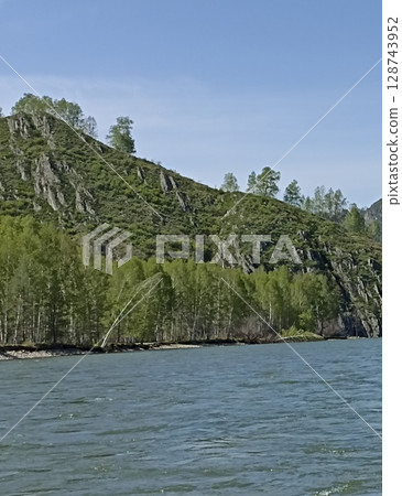 Picturesque mountain river landscape with lush vegetation and clear blue sky above scenery 128743952