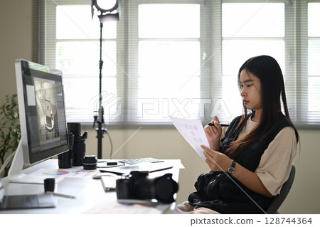 Female graphic designer reviewing color swatches, working at a creative workstation Female graphic designer reviewing color swatches, working at a creative workstation 128744364