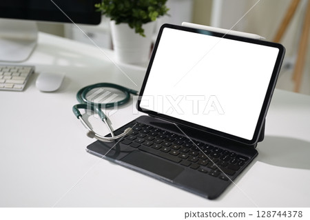 Digital tablet with blank screen and stethoscope on desk. Modern healthcare technology concept 128744378