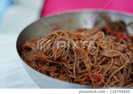 Close-Up of Korean Buckwheat Noodles with Spicy Sauce and Vegetables in Metal Bowl Close-Up of Korean Buckwheat Noodles with Spicy Sauce and Vegetables in Metal Bowl 128744830