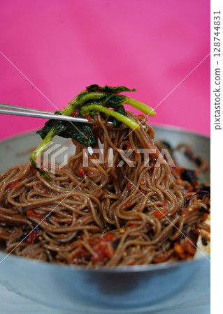 Close-Up of Korean Buckwheat Noodles with Spicy Sauce and Vegetables in Metal Bowl 128744831