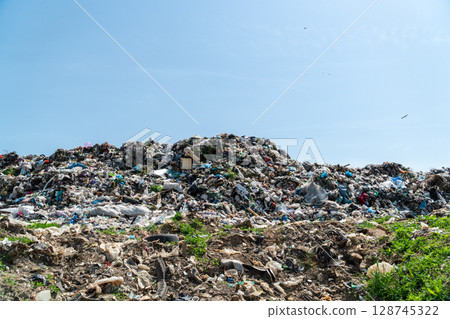 A massive pile of waste sits in a landfill under a blue sky, raising concerns about the environment and waste management 128745322