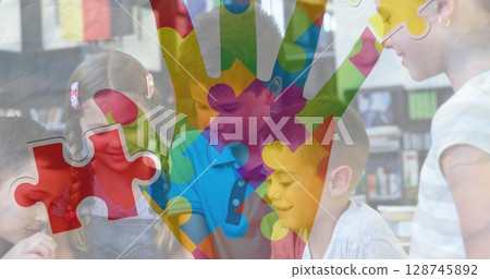Jigsaw puzzle and hand icon against diverse group of students using digital tablet at school Jigsaw puzzle and hand icon against diverse group of students using digital tablet at school 128745892