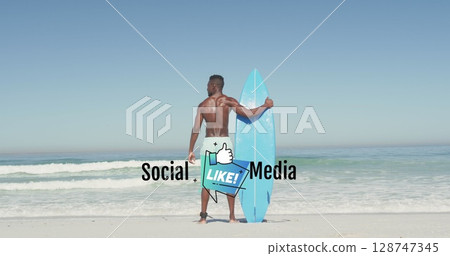 Holding blue surfboard surfer wearing swim trunks gazing at ocean on sandy beach, with surf leash 128747345