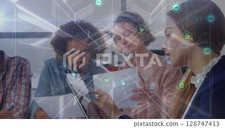 Image of network of connections with icons over diverse female and male coworkers in office 128747413