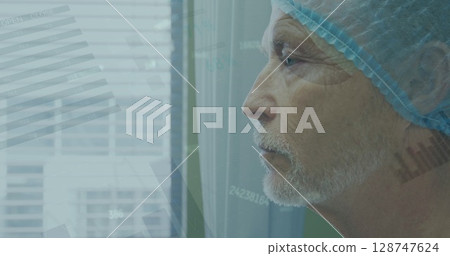 Statistical data processing over caucasian male senior surgeon looking out of the window at hospital 128747624