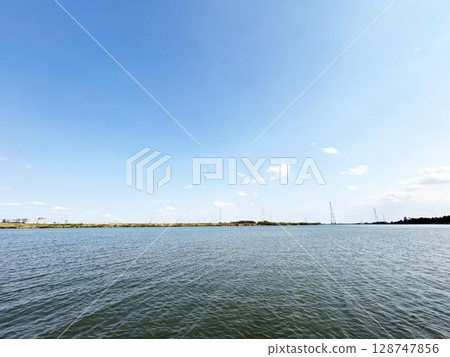 A view of a calm blue sky and a wide river A view of a calm blue sky and a wide river 128747856