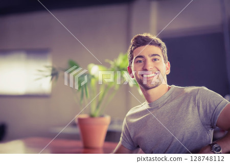 male in his twenties sitting in office lounge smiling at camera wearing wristwatch, copy space 128748112
