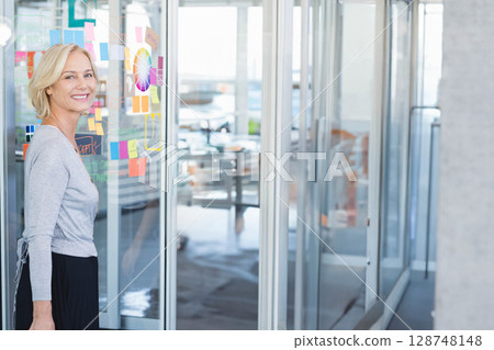 Woman standing at glass wall in office with notes, color wheel and annotations, copy space 128748148