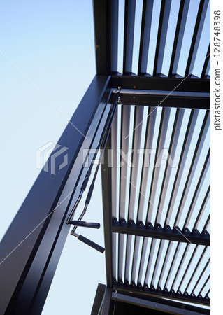 steel roof louver mechanism. patio canopy with blue sky background 128748398