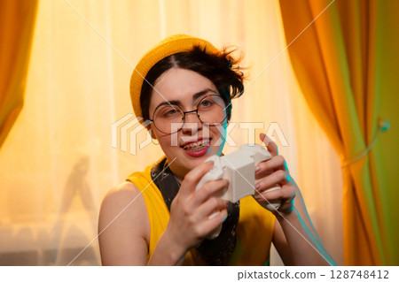 Portrait of teen girl holding controller close to chest and smiling. Concept of personal joy and gaming passion. Portrait of teen girl holding controller close to chest and smiling. Concept of personal joy and gaming passion. 128748412