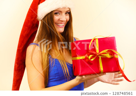 Woman in santa claus hat holds gift box. Christmas time Woman in santa claus hat holds gift box. Christmas time 128748561