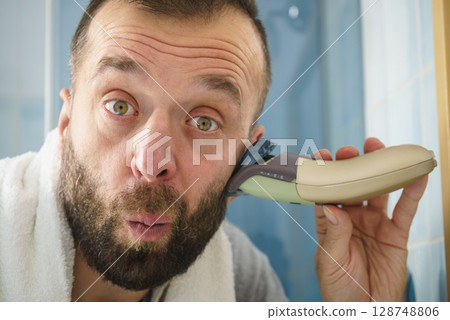 Man shaving trimming his beard Man shaving trimming his beard 128748806