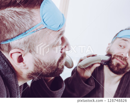 Man shaving trimming his beard Man shaving trimming his beard 128748826