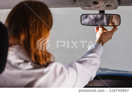 Man in car looking at mirror inside Man in car looking at mirror inside 128748967