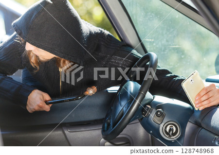 Burglar thief breaking into car stealing smartphone Burglar thief breaking into car stealing smartphone 128748968