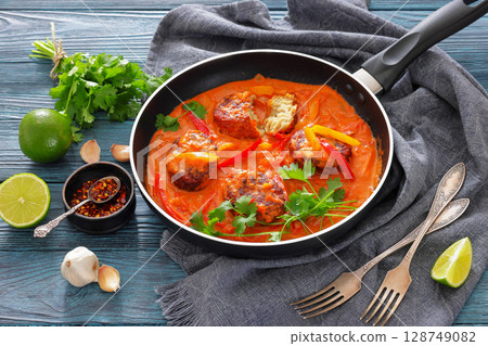 fish cakes in tomato vegetable coconut milk sauce 128749082